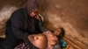 FILE - Lucy Mbewe, a traditional birth attendant attends to a pregnant woman at her home, in Simika Village, Chiradzulu, southern Malawi on Sunday, May 23, 2021.W