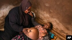 FILE - Lucy Mbewe, a traditional birth attendant attends to a pregnant woman at her home, in Simika Village, Chiradzulu, southern Malawi on Sunday, May 23, 2021.W
