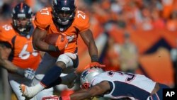 Knowshon Moreno de los Broncos salta sobre Duron Harmon, de los Patriotas, en el juego que definió la Conferencia Americana.