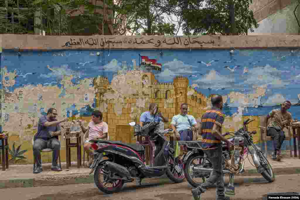 A cafe features a weathered mural of the at-risk Qaitbay Citadel. “The rising humidity and sea levels are posing major threats to our heritage sites,” says Dina Gohar. “Still, people have many careless practices.” Alexandria, Egypt, Sept. 20, 2024.