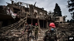 Azerbaijani soldiers and firefighters search for survivors after what officials said was rocket fire by Armenian forces, Oct. 11, 2020, in Ganja, Azerbaijan. Officials in the disputed Nagorno-Karabakh region called the attack claim a lie.