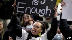 A woman holds a sign as protesters gather in Sydney, Tuesday, June 2, 2020, to support the cause of U.S. protests over the death of George Floyd and urged their own governments to address racism and police violence.