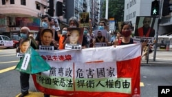 Pro-democracy demonstrators hold up a banner and portraits of jailed Chinese civil rights activists, lawyers and legal activists as they march to the Chinese liaison office in Hong Kong, June 25, 2020. 
