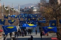 FILE - Kosovo's flags decorate a street as people walk during its 12th independence anniversary, in the capital Pristina, Feb. 17, 2020.