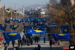 FILE - Kosovo's flags decorate a street as people walk during its 12th independence anniversary, in the capital Pristina, Feb. 17, 2020.