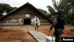 A municipal health worker and an environmental military police officer carry the AstraZeneca/Oxford vaccine as they enter in an Indigenous hut at the the Sustainable Development Reserve of Tupe in the Negro river banks in Manaus, Brazil, Feb. 9, 2021.