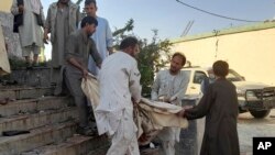 人们将一名受害者抬出遭到自杀炸弹袭击的昆都士一座清真寺。(2021年10月8日)