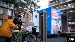 FILE - A man receives a dose of COVID-19 vaccine outside a vaccination truck parked near his residential building in the Parisian suburban city of Stains, March 2, 2021. 