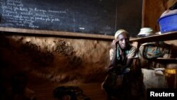 FILE - An internally displaced Congolese woman and her child sit inside a classroom used by victims of ethnic violence in Iga Barriere, Ituri province, in the eastern Democratic Republic of Congo, June 24, 2019. 