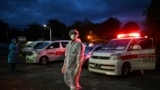 This photo taken on October 17, 2020 shows volunteers wearing personal protective equipment (PPE) waiting next to ambulances as they prepare to transfer local residents suspected of having the COVID-19 coronavirus to a quarantine centre in Yangon. (Photo 