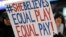 FILE - A girl holds up a sign for equal pay for the U.S. women soccer players, April 4, 2017, during a soccer match between the United States and Colombia, in East Hartford, Conn. A new study finds women are just as ambitious as men, but fall behind if their employer isn't encouraging. That gap often leads to a pay gap. 