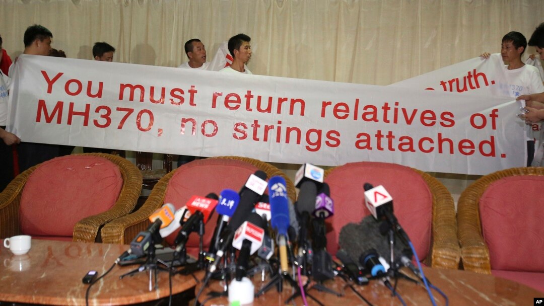 Chinese relatives of passengers on board the missing Malaysia Airlines flight MH370 hold a sign as they speak to reporters at a hotel in Subang Jaya, Malaysia, March 30, 2014.