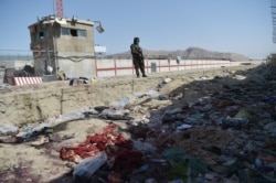 A Taliban fighter stands guard at the site of the August 26, 2021, suicide bomb attack, which killed scores of people, including 13 US troops, at Kabul airport. (Wakil Kohsar/AFP)