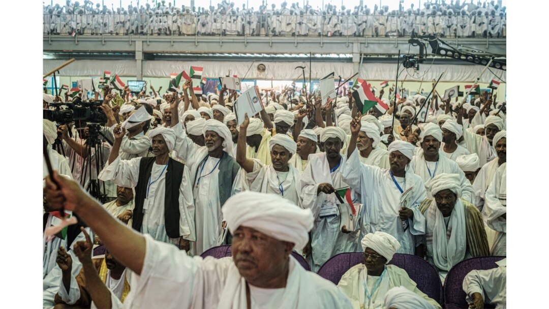 FILE - Supporters of Sudanese General Mohamed Hamdan Dagalo, also known as Himediti, deputy head of Sudan's ruling Transitional Military Council (TMC), raise up their sticks during a meeting with the General in the capital Khartoum, June 18, 2019.