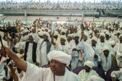 FILE - Supporters of Sudanese General Mohamed Hamdan Dagalo, also known as Himediti, deputy head of Sudan's ruling Transitional Military Council (TMC), raise up their sticks during a meeting with the General in the capital Khartoum, June 18, 2019.