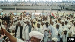 FILE - Supporters of Sudanese General Mohamed Hamdan Dagalo, also known as Himediti, deputy head of Sudan's ruling Transitional Military Council (TMC), raise up their sticks during a meeting with the General in the capital Khartoum, June 18, 2019. 