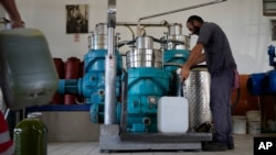 Flamour Metaj, a worker from Albania, fills a tank with olive at an olive mill in Spata suburb, east of Athens, Greece, Monday, Oct. 23, 2023.