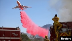 Cal Fire firefighters look on as a plane drops fire retardant on the Maria Fire in Santa Paula, Calif., Nov. 1, 2019.