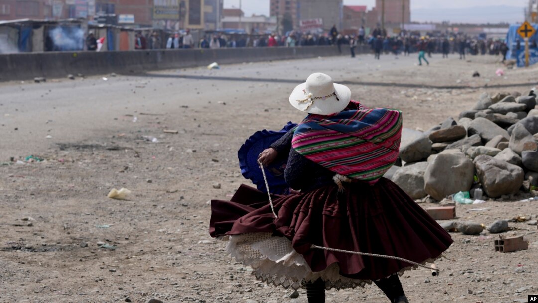 ARCHIVO - Una partidaria del expresidente Evo Morales arroja una piedra a los partidarios del actual presidente Luis Arce en El Alto, Bolivia, el 22 de septiembre de 2024.