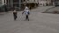 A woman and a girl walk wearing protective head coverings walk on a street covered with volcanic ash a day after the La Soufriere volcano erupted, in Kingstown, on the eastern Caribbean island of St. Vincent, April 10, 2021.