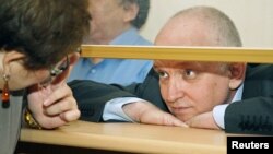 Vladimir Kozlov, leader of the unofficial Alga! party, looks out from a glass-walled cage during his trial in the Kazakh city of Aktau, October 8, 2012. 