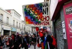 A demonstrator holds a placard that reads "Bolivia Force, Resist, Camacho coup" during a protest against Chile's government in Valparaiso, Chile, Nov. 12, 2019.