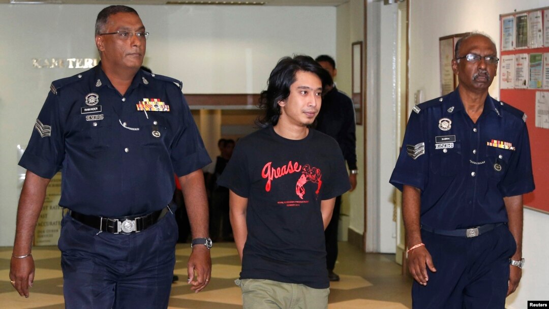 Aktivis Malaysia Adam Adli dikawal polisi di pengadilan di Kuala Lumpur, 2013.