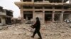 A man carries his belongings through a street destroyed in recent bombings by the Syrian government forces in the town of Sarmin, in Idblib province, Syria, Feb. 7, 2020.