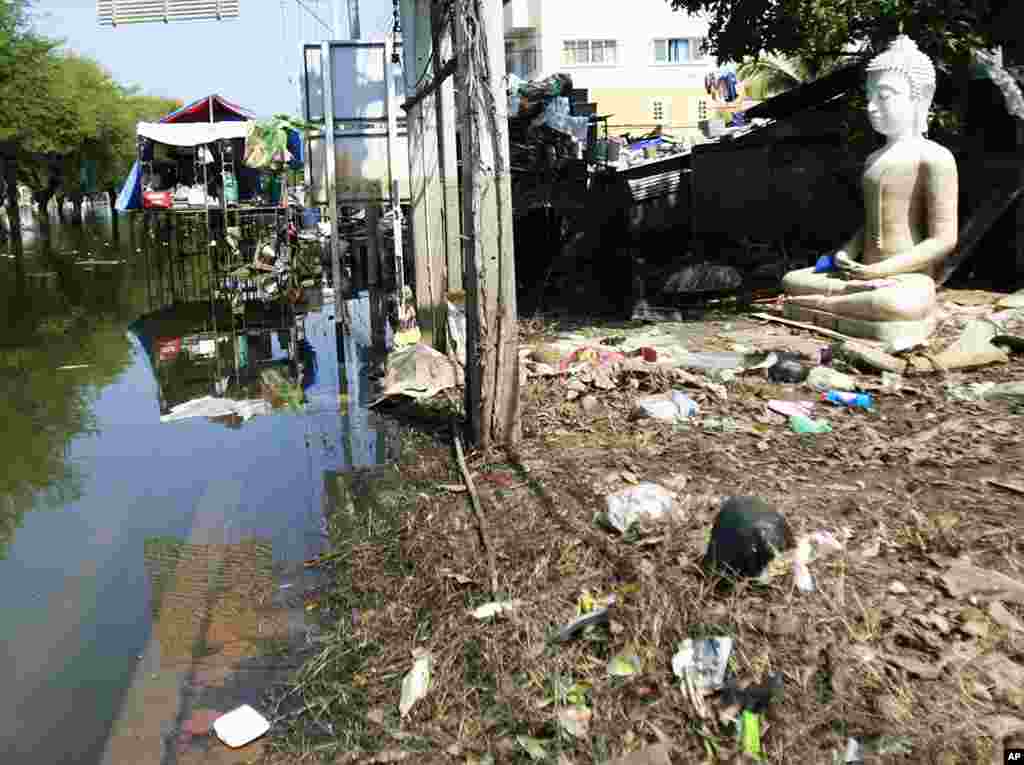 A Buddha's statue sits amidst trash at a half-flooded street corner in Ayutthaya province, central Thailand November 8, 2011. (AP)