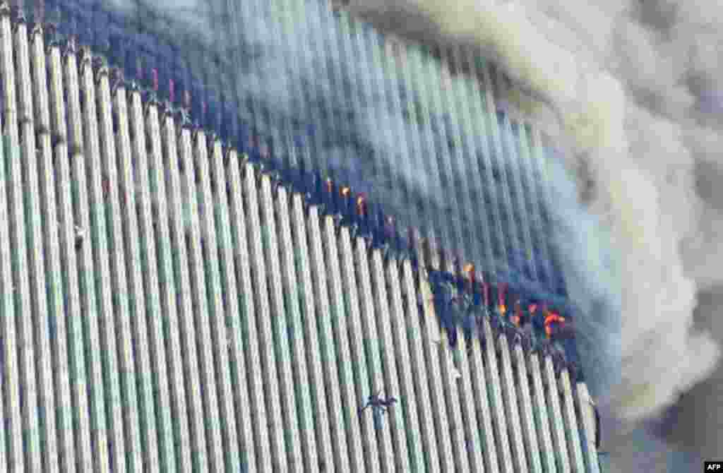 A person falls from the north tower of New York's World Trade Center as another clings to the outside, left center, while smoke and fire billow from the building, Tuesday Sept. 11, 2001. Terrorists crashed two hijacked airliners into the World Trade Cente