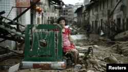 A woman sits on the ruins after typhoon Nepartak swept through Minqing county, Fujian province, China, July 10, 2016.