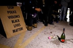 A sign, a bottle of alcohol and flowers are left in tribute to victims of a shooting during Tuesday night's protests, at the site of the incident, during a protest following the police shooting of Jacob Blake, in Kenosha, Wis., Aug. 26, 2020.