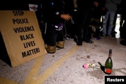 A sign, a bottle of alcohol and flowers are left in tribute to victims of a shooting during Tuesday night's protests, at the site of the incident, during a protest following the police shooting of Jacob Blake, in Kenosha, Wis., Aug. 26, 2020.