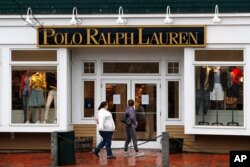 Women read a notice announcing the temporary closure of a Polo Ralph Lauren store in Freeport, Maine, March 17, 2020.