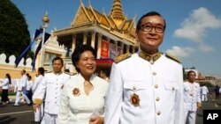 In this file photo taken on Oct. 29, 2014, Sam Rainsy, acting president of the outlawed Cambodia National Rescue Party (foreground) walks together with his wife Tioulong Saumura, after attending a celebration marking 10th anniversary of King Sihamoni, in Phnom Penh. 