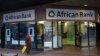 FILE - A cleaner walks past a branch of African Bank in Cape Town.