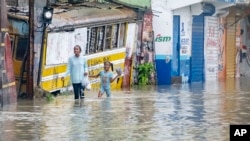 People walk through a street flooded by the rains of Tropical Storm Franklin in Santo Domingo, Dominican Republic, Aug. 22, 2023. 