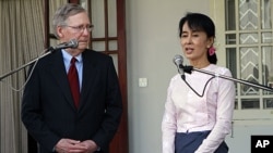 U.S. Senator Mitch McConnell, left, listens to Burmese pro-democracy leader Aung San Suu Kyi talk to journalists during a press conference after their meeting at her home in Rangoon, January 16, 2012.