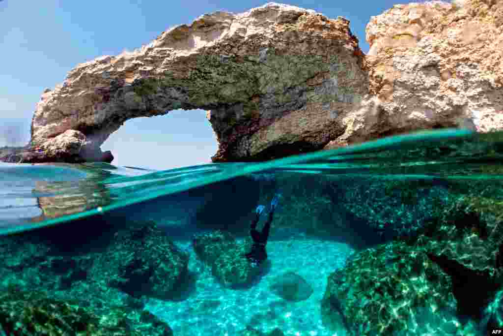 Cypriot marine ecologist Louis Hadjioannou dives below the water&#39;s surface to photograph the coral to monitor the impact of climate change in the crystal clear waters of Glyko Nero in Ayia Napa, off the island&#39;s southeastern shore, Cyprus.