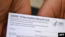 FILE - A health care worker displays a COVID-19 Vaccination Record Card at QueensCare Health Center in Los Angeles, California, Aug. 11, 2021.