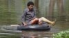 A Cambodian woman rides on a tire tube in a flooded road in Kampong Thom province, about 120 kilometers (75 miles) north of Phnom Penh.