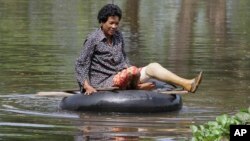 A Cambodian woman rides on a tire tube in a flooded road in Kampong Thom province, about 120 kilometers (75 miles) north of Phnom Penh.