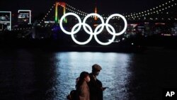 Un homme et une femme marchent non loin du symbole des JO, Tokyo, le 1er décembre 2020. 