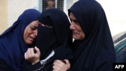 Palestinian women react upon identifying the bodies of victims of an Israeli strike that targeted a mosque-turned-shelter in Deir al-Balah in the central Gaza Strip, in the courtyard of the al-Aqsa Martyrs hospital on Oct. 6, 2024.