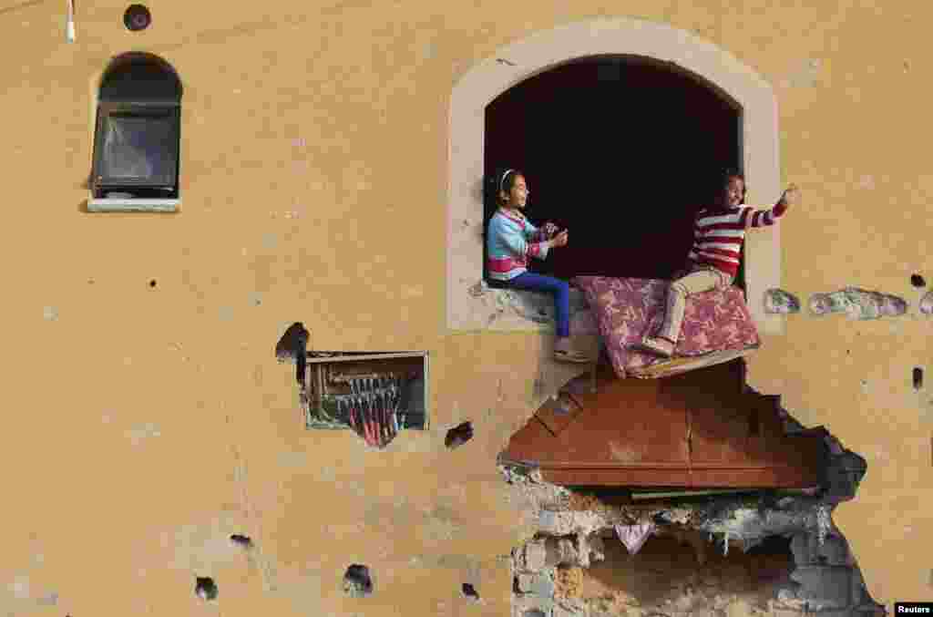 Meninas palestinas brincam à jabela de casa, que testemunhas dizem ter sido danificada por ataques de Israel durante uma guerra de 50 dias no verão enterior, em Khan Younis, situada no sul da Faixa de Gaza.