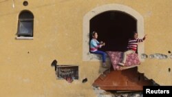 Imagem de arquivo - meninas palestinianas à janela de uma casa que tinha sido bombardeada durante a guerra dos 50 diasna Faixa de Gaza. Março 10, 2015