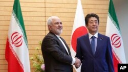 Thủ tướng Nhật Bản Shinzo Abe (phải) bắt tay Ngoại trưởng Iran Mohammad Javad Zarif trong một chuyến thăm của người đứng đầu ngành ngoại giao Iran tới Tokyo hôm 16/5. Ông Abe dự định sẽ đi thăm Iran trong tuần tới.