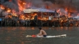 A man watches houses on fire at Tondo in Manila, Philippines.&nbsp;Raging orange flames and thick black smoke billowed into the sky, as fire ripped through hundreds of houses in a closely built slum area of the capital.