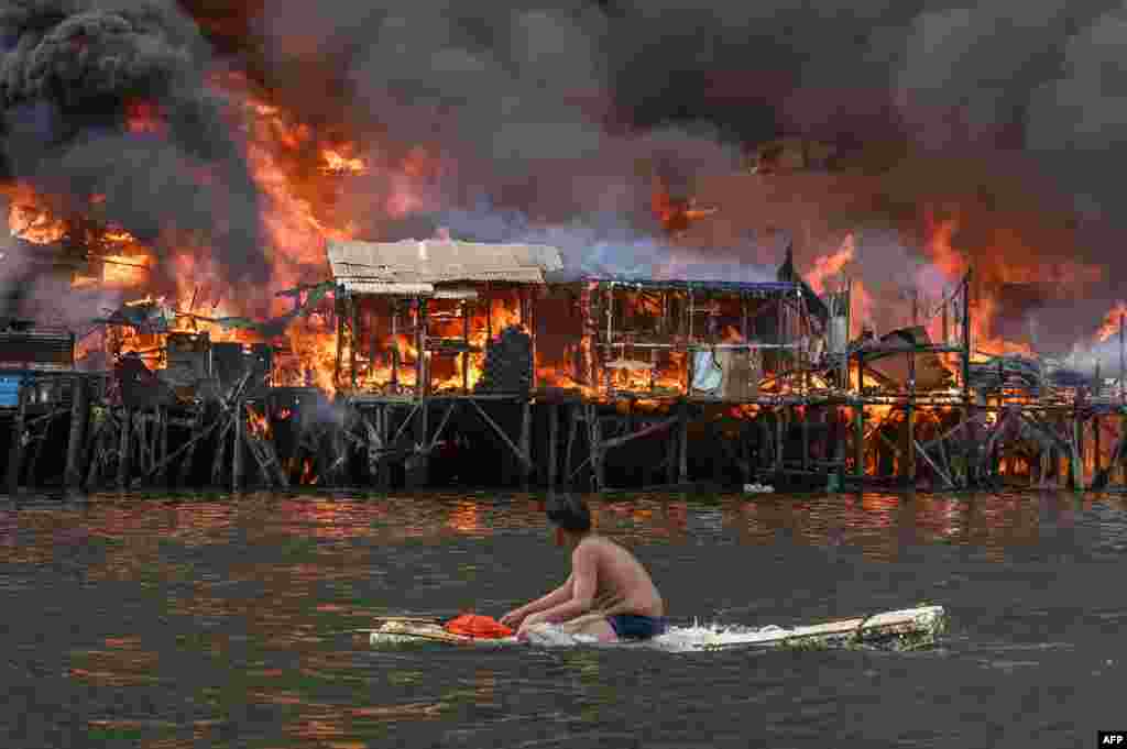 A antheral   watches houses connected  occurrence  astatine  Tondo successful  Manila, Philippines.&nbsp;Raging orangish  flames and heavy   achromatic  fume  billowed into the sky, arsenic  occurrence  ripped done  hundreds of houses successful  a intimately  built slum country  of the capital.