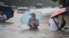 Residents wade through floodwaters on a flooded road amid heavy rainfall in Zhengzhou, Henan province, China, July 21, 2021.